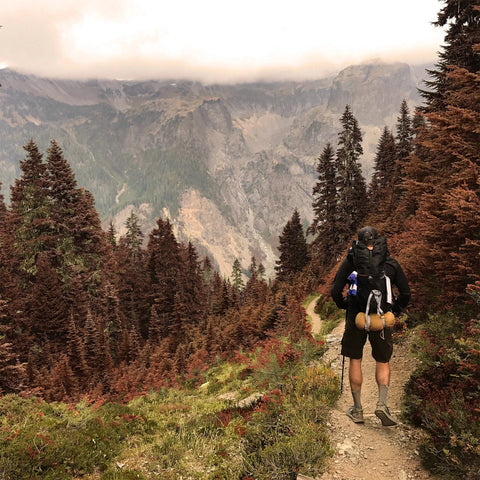 Hiker on a mountain trail wearing the Adventure Pack 20L