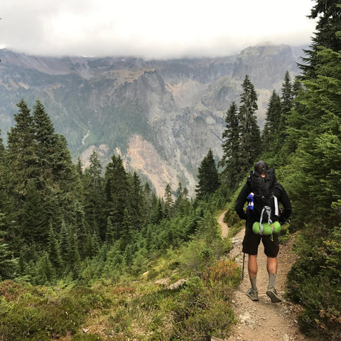 Hiker on a forest trail wearing the Adventure Pack 20L
